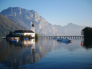 Distant church on an island in the middle of the lake with mountains in the background and jet skis.