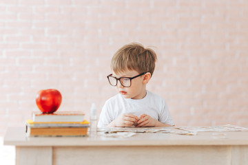 Fototapeta na wymiar The child is studying at home, studying at home during quarantine, educational games for children, teaching gifted children, children of genius. boy sitting ubfocused glasses in focus. Concept problem