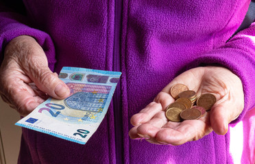 Woman's hands are holding a few euro coins. Pension, poverty, social problems and the theme of old...