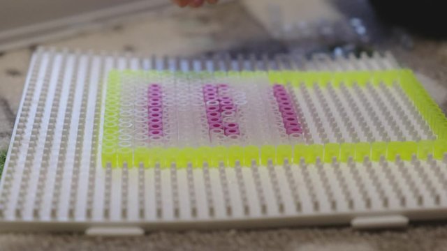 Kinderh&auml;nde spielen mit Steckperlen