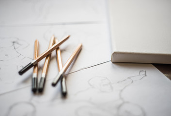 A top view flat lay of many figure drawing pencil and marker sketches. The artist worskspace with male and female drawings and pencils on the white paper, art, craft, creativity, inspiration, concepts