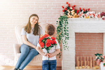 Boy holding a bouquet of flowers behind his back, the son gives his mother flowers, what to present...