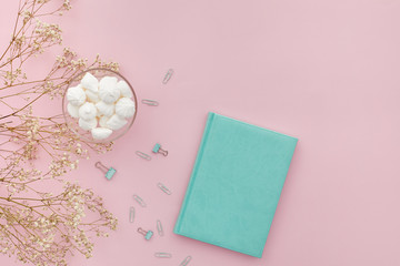 flat lay gypsophila flowers and a diary on pink background, top view. empty space for text.