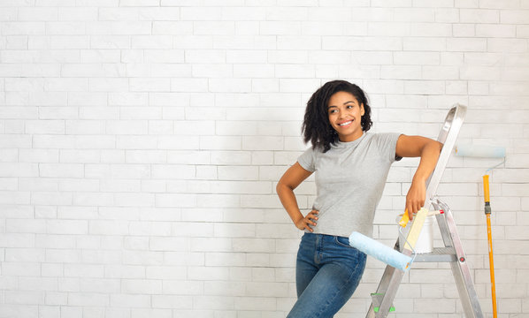 African american woman on stepladder with paint roller
