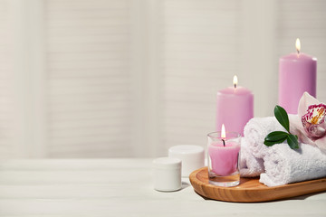 Fototapeta na wymiar Spa products with aromatic candles, orchid flower and towel on white wooden table. Beauty spa treatment and relax concept. copy space