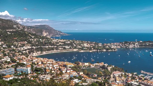 Aerial time lapse from on top of a hill in Nice looking down at boats, yachts and ships moving across the water in the Rade de Villefranche-sur-Mer in Saint Jean Cap Ferrat, France.