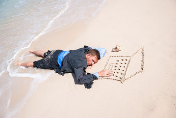 Businessman falling asleep working in isolation at his sand laptop on the beach with waves washing at his feet