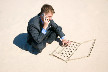 Telecommuting businessman multitasking between talking on his mobile phone and typing on a laptop...