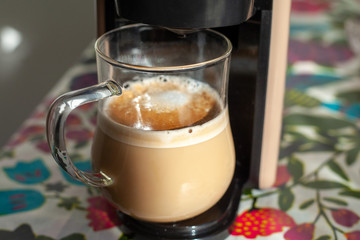 transparent cup stands in a cappuccino coffee machine