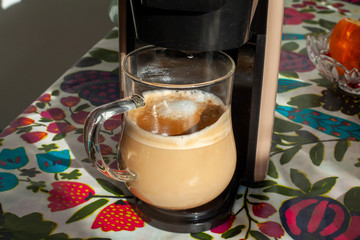 transparent cup stands in a cappuccino coffee machine