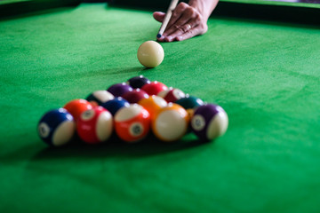 Man's hand and Cue arm playing snooker game or preparing aiming to shoot pool balls on a green...