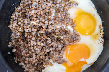In the pan is cooked buckwheat and two fried eggs.