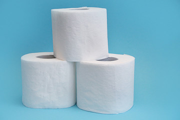 white rolls of toilet paper stand pyramid on blue background