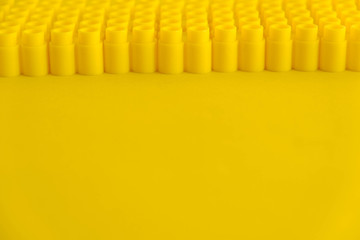 Yellow plastic building blocks on yellow background. Background of plastic details building blocks....