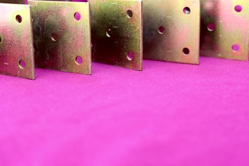 Arrow made of brackets isolated on pink. Metal corners are directed to the left with a place for the text. Golden metal bracket on a purple background. Metal corners frames, borders. Isolated.
