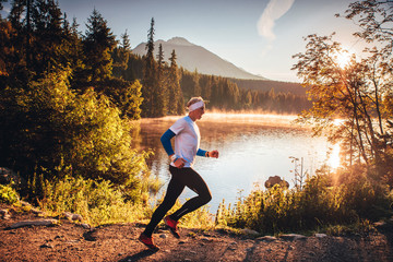 Alone trail runner in orange morning nature in mountains