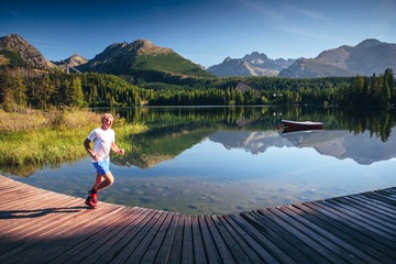 Fototapeta premium Morning free run in trail by mountains and lake, Strbske pleso, Slovakia