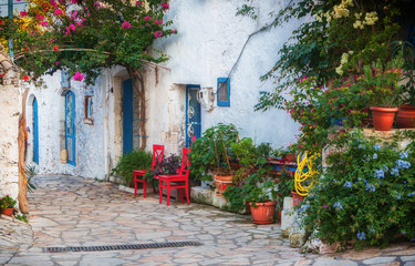 Fototapeta na wymiar Gasse auf der Insel Korfu. Rote Stühle und blaue Türen.