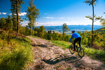 Mountain biking man riding downhill on bike at autumn mountains forest landscape. Outdoor sport...