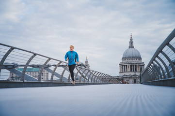Alone runner in empty streets of london in Coronavirus, Covid-19 quarantine time. Millennium Bridge...