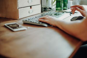 Woman typing on a keyboard working in home office.