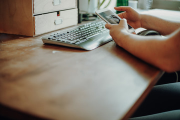 Woman checking on her smartphone while working from home.