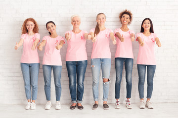 Obraz premium Women In Pink Awareness T-Shirts Gesturing Thumbs-Up Over White Wall