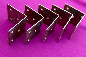 Arrow made of brackets isolated on pink. Metal corners are directed to the right with a place for...