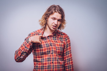 Closeup portrait of young man opening shirt to vent,it's hot. Negative emotion, facial...
