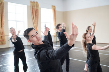 Young handsome man with outstretched arms doing one of dance exercises