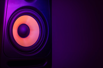 Music studio speaker, with a yellow membrane, isolated on a dark purple background, with space for...