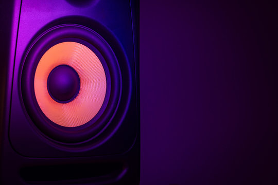 Music studio speaker, with a yellow membrane, isolated on a dark purple background, with space for text on the right side. Electronic music concept