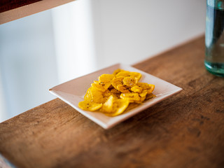 Banana chips on a white rectangular plate on a wooden table
