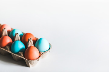 Painted easter eggs in carton box on white background. Trendy blue and red color. Top view. Paschal concept.