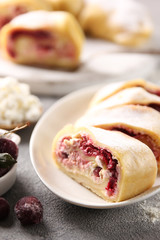 Oriental cuisine. Khanum is a dish of Uzbek cuisine. Dough with cottage cheese, sugar and cherries in the form of a roll steamed. Dish on a white plate on a light grey background. Background image