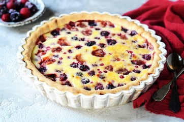 Tart with berries in sour cream filling on a gray background