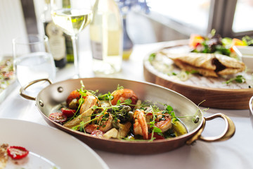Grilled prawns shrimps with vegetables in a metal bowl on white table, side view, horizontal
