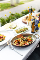 White table served with delicious italian food, vertical, side view, vegetables, chicken, grill, seafood