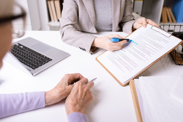 Hands of insurance agent underlining important phrase in document