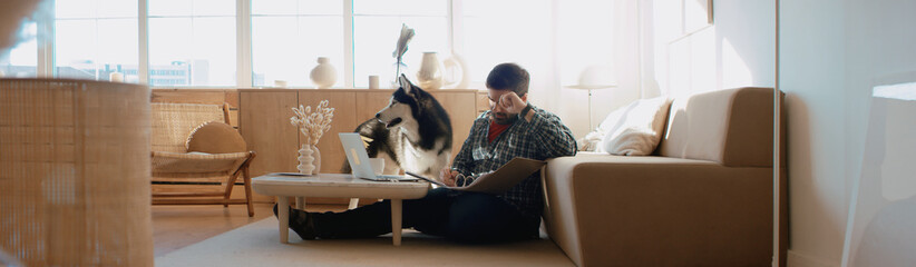 Middle Eastern male working from home, having a video call, dog sits near him. Stay home, quarantine remote work