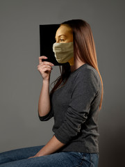 Happy world book day 2020, be safe and read to become someone else - woman covering face with book in mask while reading on grey studio background. Celebrating, education, art, protection concept.