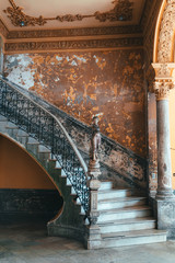 Old concrete shabby rounded staircase with a statue in an old Spanish-style colonial house