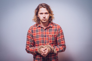 Fototapeta premium Tortured business man holding his hands tied with a rope