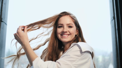 Cheerful Young Girl Playfully Touches Her Hair.