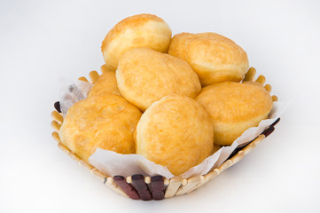 Lush fried donuts in a wooden basket on a white background