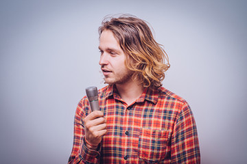 handsome man singing to the microphone. Emotional portrait of an attractive guy a gray background