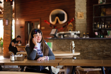 beautiful girl resting and talking on the phone in a cafe ski resort