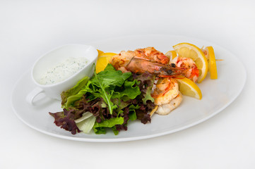 Large king prawns with slices of lemon on sticks, lettuce and white sauce with herbs