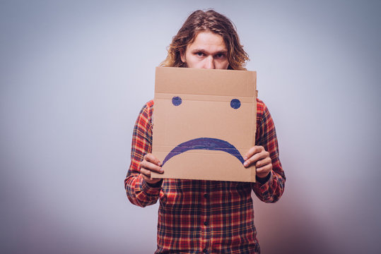 man  holding a picture with a unhappy smiley