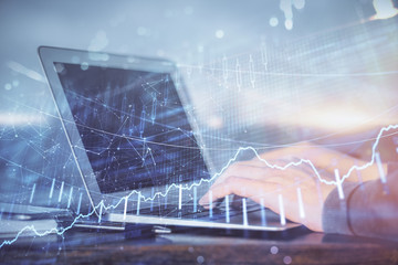 Multi exposure of stock market graph with man working on laptop on background. Concept of financial analysis.